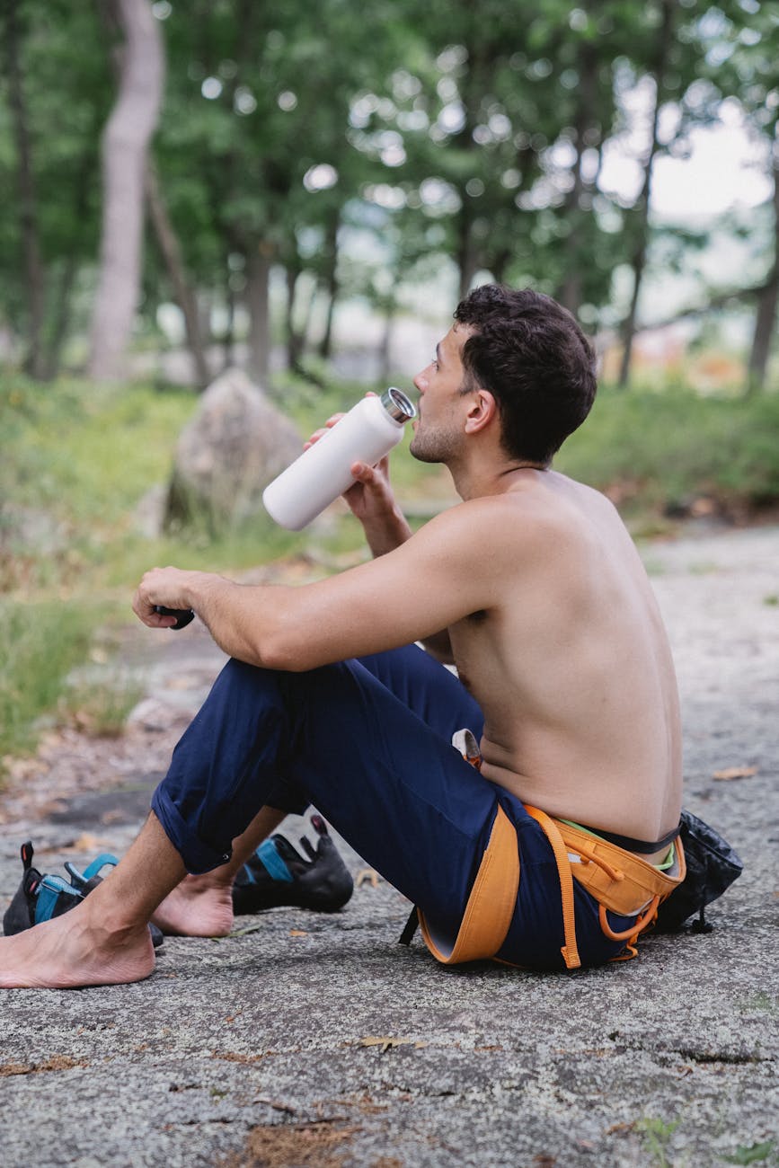 shirtless man drinking from a tumbler